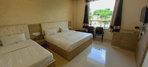 ein Hotelzimmer mit zwei Betten und einem Fenster in der Unterkunft Sanjog Resort in Kota