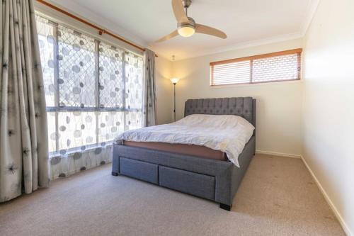 a bedroom with a bed and a large window at Immaculate House, Indulgent Living! in Brisbane