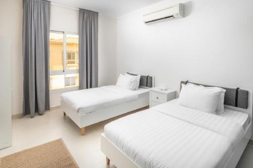 a white room with two beds and a window at Mabaat - Al Waha 19 - 377 in King Abdullah Economic City