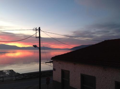 a sunset over a body of water with a building at FILIPPOS-Spectacular area,,,,panoramic,-sea- view- apartments-42m, just call on the photo number, for price,vacancy etc,,-next to Vallis hotel,, 15meters from seaside!!! in Agria