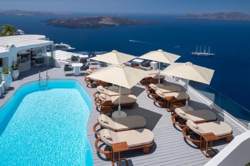 a deck with chairs and umbrellas and a swimming pool at Sun Rocks Boutique Hotel in Firostefani