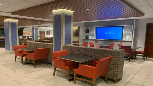 a restaurant with tables and chairs and a flat screen tv at Holiday Inn Express & Suites - Middletown by IHG in Middletown