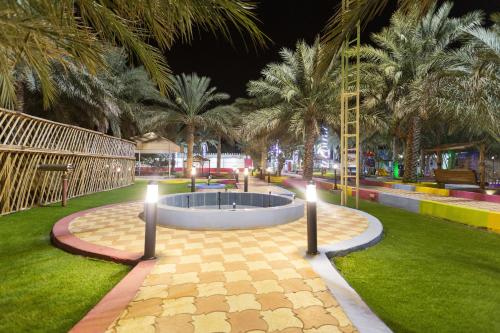 uma fonte num parque com palmeiras à noite em بيرحاء إبراء للسياحة em Ibrā