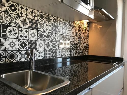 Apartamentos Ciudad de Ronda في روندا: مطبخ مع حوض وبلاط اسود وبيض