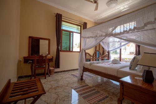 a bedroom with a bed and a desk and a window at Sunny Palms Beach Bungalows in Uroa