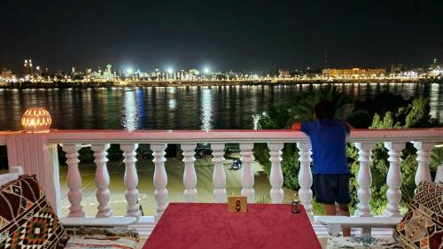 a man standing on a white railing looking at the water at El Mesala Hotel in Luxor