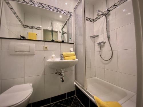 a bathroom with a sink and a shower and a toilet at Hotel Ambiente et Art in Düsseldorf