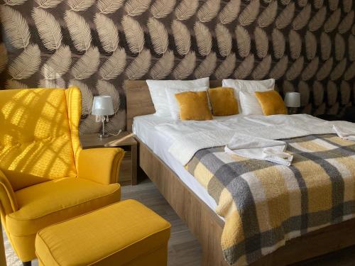 - une chambre avec un lit et une chaise jaune dans l'établissement Libra Hotel, à Veresegyház