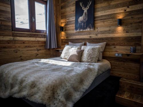 um quarto com uma cama com paredes de madeira e uma janela em Magnifique Duplex Oneigedor Départ ski aux pieds et vue montagne em Tignes