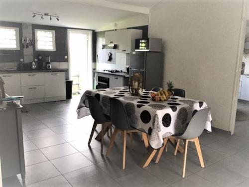 une table noire et blanche avec des chaises et une cuisine dans l'établissement La Case Michou, calme et confort, à La Plaine-des-Palmistes