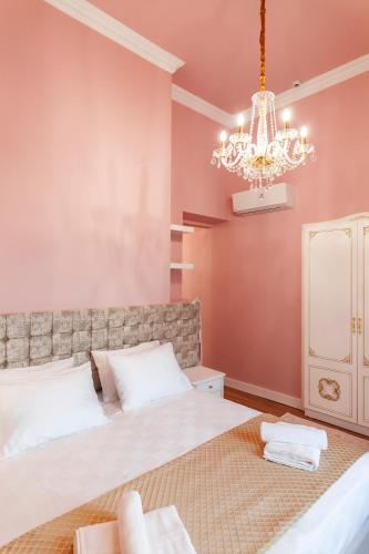 a bedroom with a large bed and a chandelier at Via Villa Iliotti Rhodos in Rhodes Town
