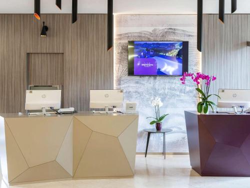 a lobby with a reception desk with a tv on the wall at Mercure Roma Centro Colosseo in Rome