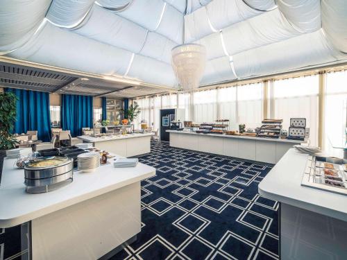 a restaurant with white counters and blue and white floors at Mercure Montpellier Centre Antigone in Montpellier