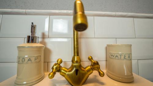 a bathroom sink with a gold faucet and a bottle of water at Groc Rooms in La Seu d'Urgell
