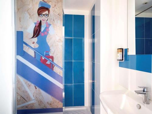 a bathroom with a painting of a woman on a staircase at greet Hotel Bordeaux Aeroport in Mérignac
