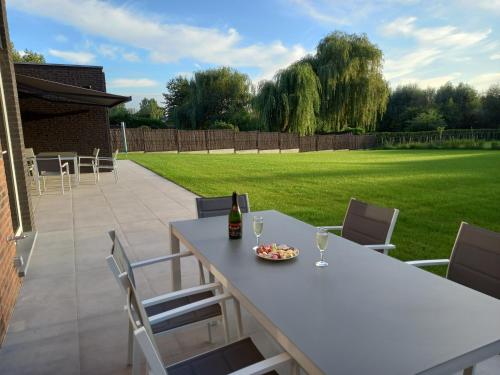 a table and chairs with a bottle of wine and a plate of food at Les jardins du Gauquier in Frasnes-lez-Buissenal