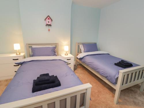 two beds in a bedroom with purple sheets at Carlyn in Caernarfon