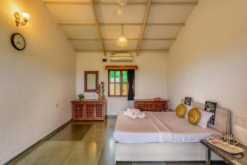 um quarto com duas camas e um relógio na parede em SaffronStays Le Soil, Igatpuri - pet-friendly villa with viewing deck for panoramic views em Igatpuri