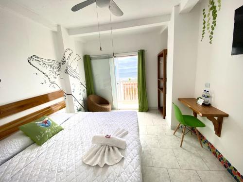 a bedroom with a bed and a desk and a window at Whale House Hotel in Puerto López