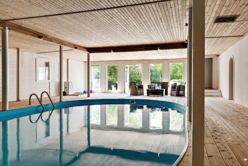 a swimming pool in a house with a wooden ceiling at Large and beautifully decorated pool house in Tomelilla, Österlen in Tomelilla