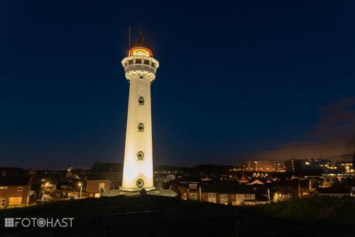 a lighthouse lit up at night in a city at Ferienhaus Abenteuer in Egmond aan Zee
