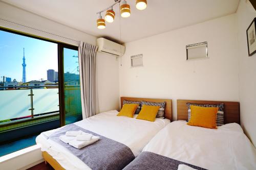 twee bedden in een kamer met een groot raam bij Skytree House In Tokyo in Tokyo