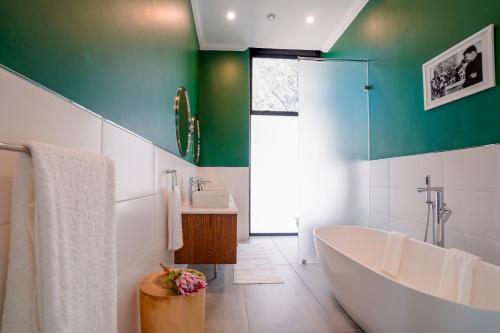 a green and white bathroom with a tub and a sink at Sanctuary Mandela in Johannesburg