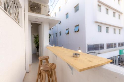 - une table en bois sur un balcon avec deux tabourets dans l'établissement Meir's Boutique Guesthouse, à Tel Aviv