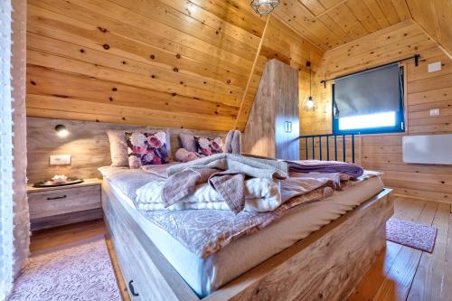 a bedroom with a large bed in a wooden room at Brvnare Lovor in Krajevi