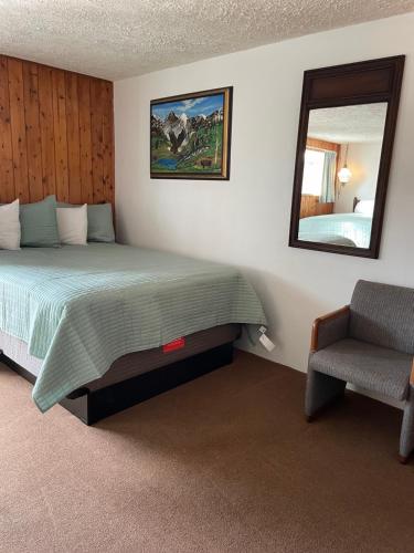 a bedroom with a bed and a mirror and a chair at adoba® Dreamland in Gulliver