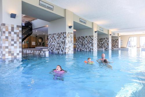 a man and two children swimming in a swimming pool at RCN Vakantiepark de Schotsman Bungalow de Bevelander in Kamperland