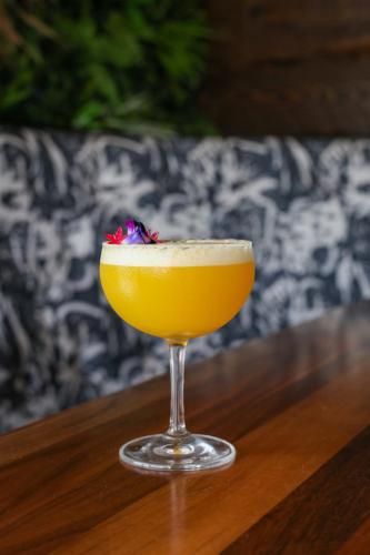 a yellow drink sitting on a wooden table at The Saint Hotel in St Pete Beach