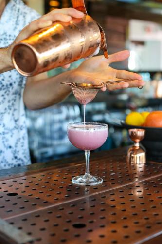 a person pouring a drink into a cocktail glass at The Saint Hotel in St Pete Beach