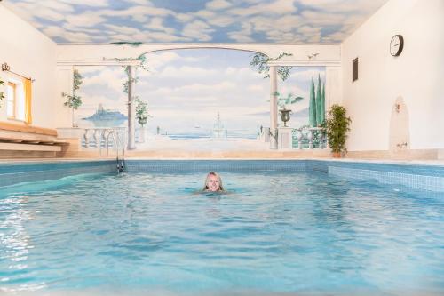 a woman is swimming in a swimming pool at Alpenhof Krün in Krün