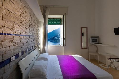Hotel Vietri Coast في فيتري: غرفة نوم بسرير أبيض مع بطانية أرجوانية