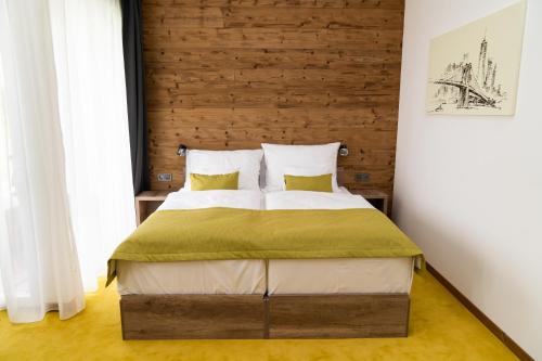 Hotel Kristály Konferencia & Wellness في Ajka: غرفة نوم بسرير كبير مع اللوح الخشبي