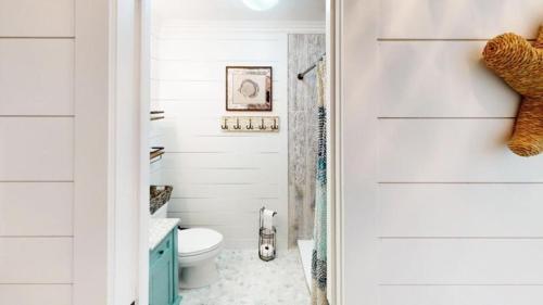 een witte badkamer met een toilet en een deur bij Beach Blossom - Bright, Updated Unit with Hot Tub on Patio in Hilton Head Island