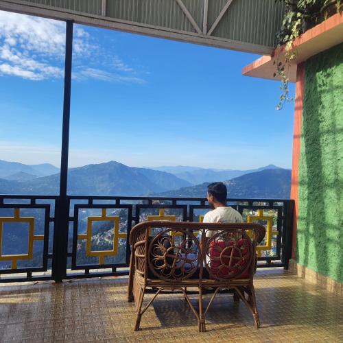 a man sitting on a bench looking out at the mountains at Great Eastern Valley Residency in Gangtok
