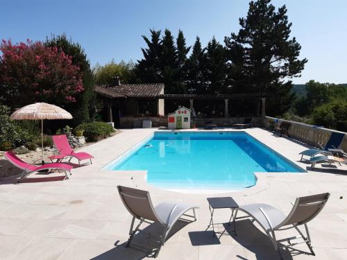 une grande piscine avec des chaises et un parasol dans l'établissement Les Chambres de Lili, à Saint-Loup