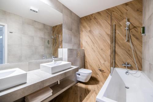a bathroom with two sinks and a tub and a toilet at Krakow Square Residence in Kraków