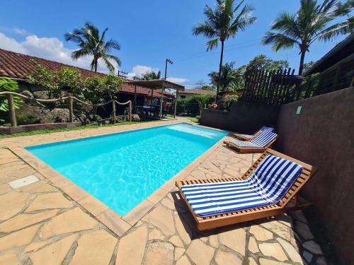 uma piscina com duas espreguiçadeiras ao lado em Pousada Por do Sol em Ilhabela