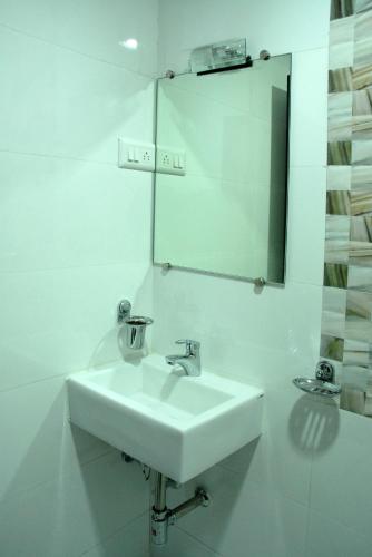 a white bathroom with a sink and a mirror at Hotel City View in Navi Mumbai