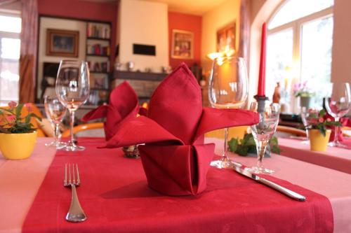 a table with a red table cloth with a red flower on it at Hotel Vinum in Niederwurschnitz