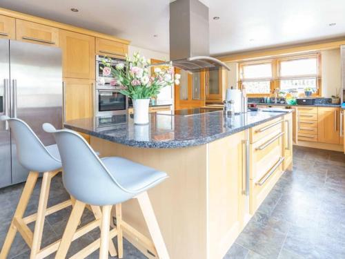 una cocina con una isla con 2 sillas y una barra en Milne's Brae, cosy, comfortable and centrally located in beautiful Braemar en Braemar