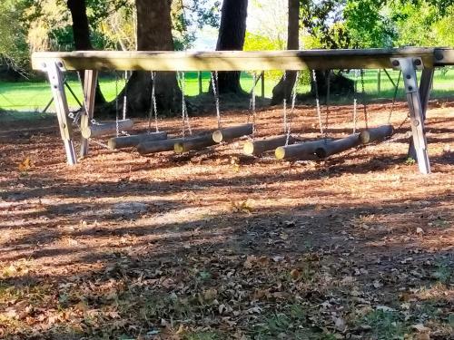 a swing seat in a park with trees at Mobilhome Salsa XXL in Gastes