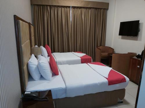 a hotel room with two beds and a television at Bliss Hotel in Dubai