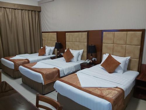 a hotel room with three beds and a desk at Bliss Hotel in Dubai