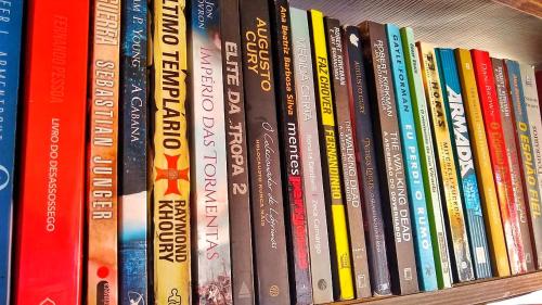 a row of books on a book shelf at Pousada João de Barro in Camaçari