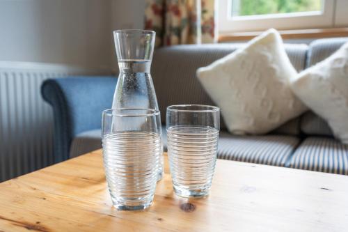 a vase and two glasses on a wooden table at Naturhotel Hüttenwirt im Grossarltal in Hüttschlag