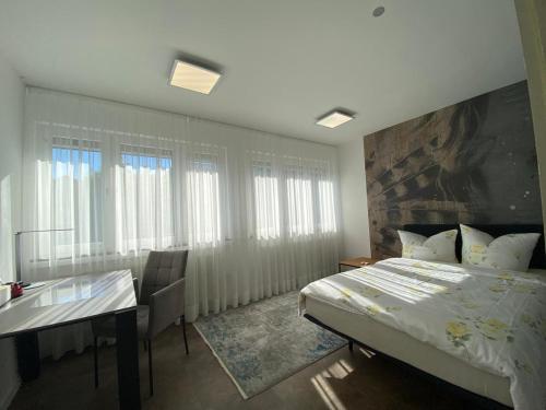 a bedroom with a bed and a desk and windows at Haus Pia Executive Apartments in Friedrichshafen